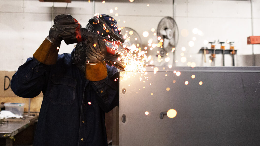 Technician grinding a metal part as sparks fly
